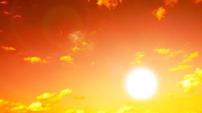 Bright sun in a clear orange sky with scattered yellow clouds, creating a warm and glowing atmosphere.