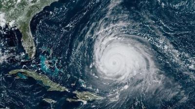Satellite image showing a large hurricane with a well-defined eye over the Atlantic Ocean, approaching the southeastern coast of the United States and the Caribbean.