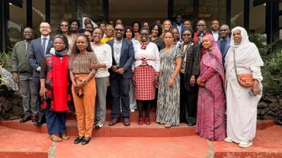 A large, diverse group of people stands together on red steps in front of a building, posing for a group photo.