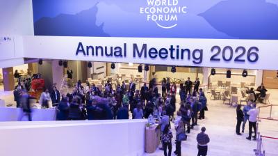 A crowd of people gathers in a spacious hall beneath a sign reading "Annual Meeting 2026" at the World Economic Forum.
