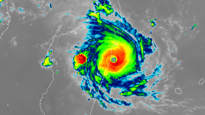 Infrared satellite image showing a strong cyclone with a defined eye making landfall on a coastal region, with intense rain bands surrounding the center.
