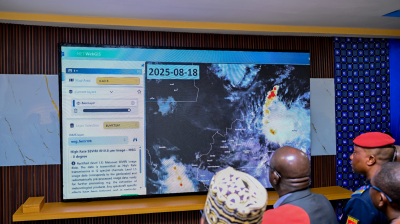 Several uniformed individuals look at a large digital screen displaying weather satellite data and maps dated 2025-08-18.