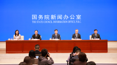 Five officials sit at a long table during a press conference, with "The State Council Information Office, P.R.C." displayed in English and Chinese on a blue screen behind them.