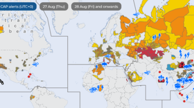 World map showing various weather alerts with colored zones and icons indicating storms, floods, and other hazards across multiple continents, including Europe, Africa, and the Americas.