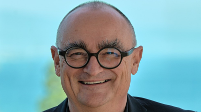 A smiling middle-aged man with round glasses.