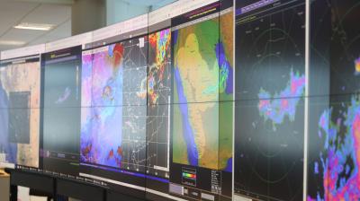 A wall of monitors displaying meteorological radar maps and weather data.