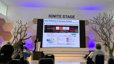 A speaker presents a slide on data definition and estimate methods at the IGNITE STAGE in a conference room, with attendees seated and some taking photos.