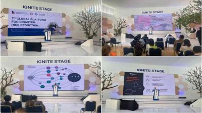 A conference speaker presents slides on disaster risk reduction at the IGNITE STAGE, with attendees seated and watching in a brightly lit room.