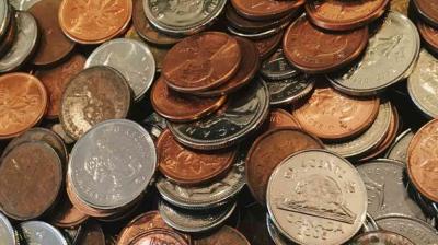A close-up of assorted Canadian coins, including pennies, nickels, and dimes, scattered and overlapping each other.