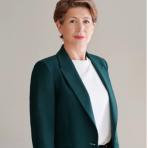 Professional woman in a green blazer posing for a portrait.