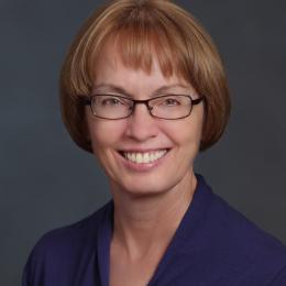 A woman wearing glasses and a purple shirt.