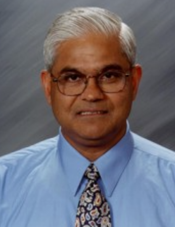 An indian man in a blue shirt and tie.