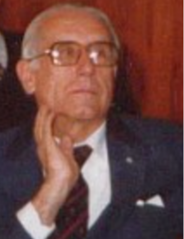 An older man wearing glasses and a suit.