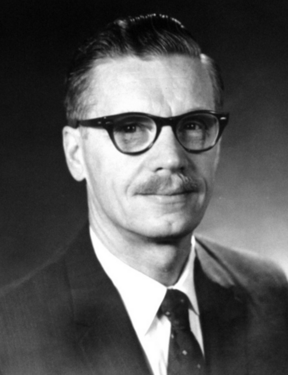 A black and white photo of a man with glasses and a mustache.