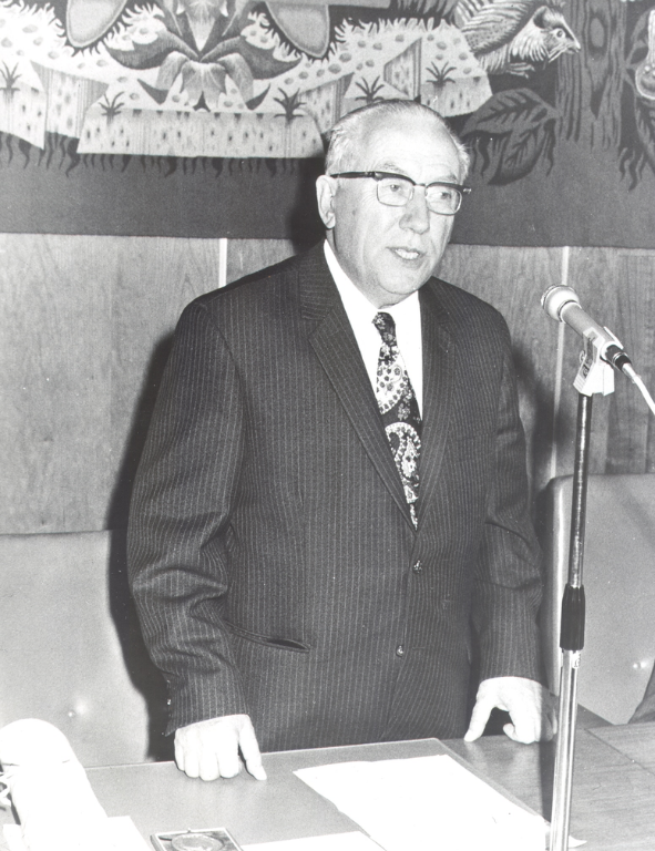 A man in a suit standing in front of a microphone.