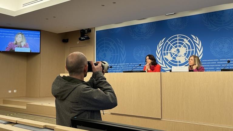 A woman takes a picture of a woman in front of a podium.