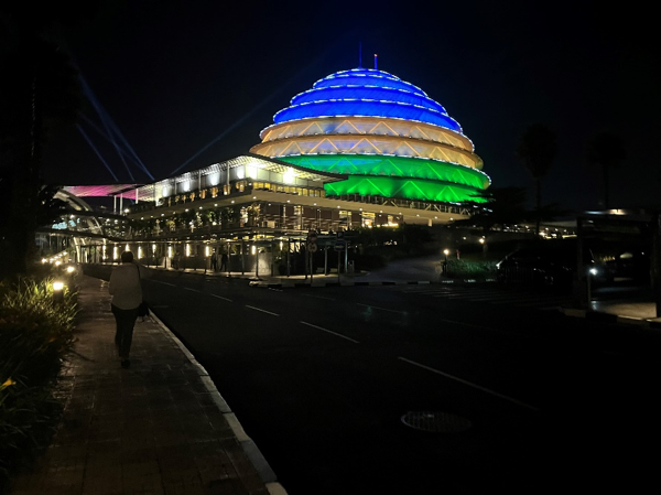 Illuminated multi-colored dome structure at night with a pedestrian walking by.