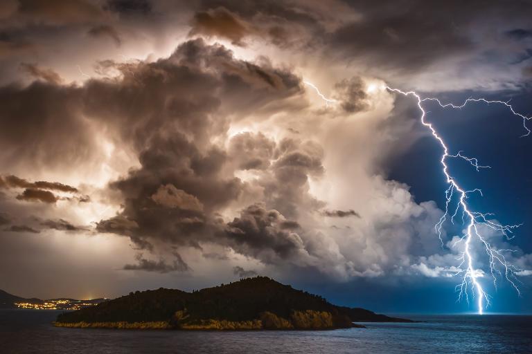 A stormy sky with dramatic clouds and lightning striking near a mountainous island surrounded by water. City lights are visible in the background on the right.