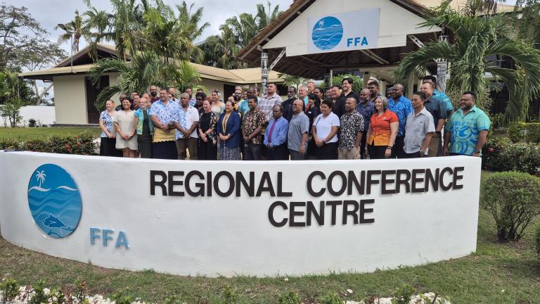 A large group of people pose for a photo in front of the FFA Regional Conference Centre building, standing behind a sign with the center's name and logo.