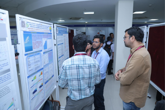 A group of people stand in front of a scientific poster display at an indoor conference, discussing the research presented.