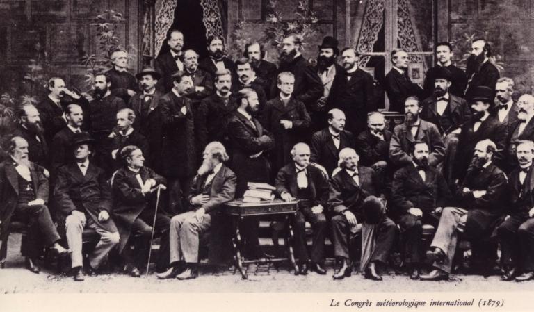 A black-and-white photo of a large group of men in suits posing together indoors at the International Meteorological Congress in  April 1879.