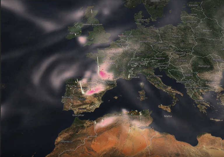 A satellite map of Western Europe and North Africa shows regions with pink and white highlights, indicating varying concentrations of atmospheric aerosols or pollution levels.