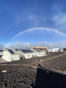 A rainbow is seen over a building with solar panels.