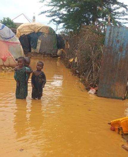 A boy standing in a flooded area near tents.