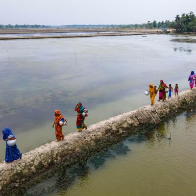 A group of women walking on a wall with water.