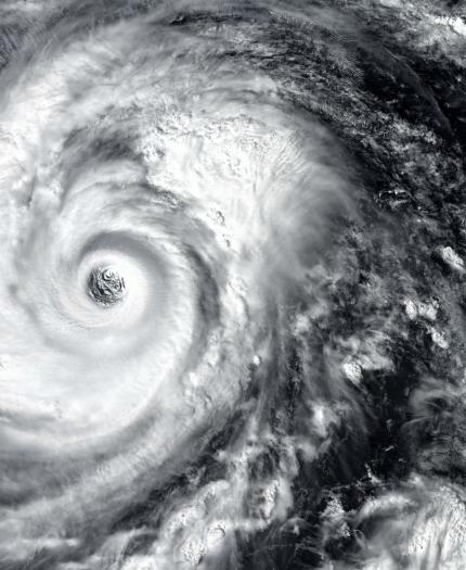 Satellite image of a large, well-defined swirling hurricane over the ocean, showing the eye and surrounding cloud structure.