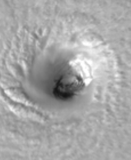 Satellite image of a hurricane's eye viewed from above, showing swirling cloud patterns.