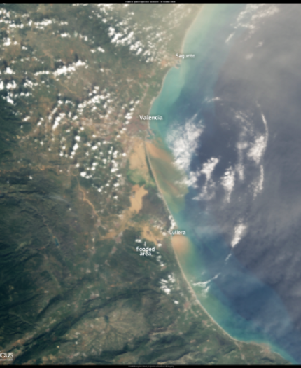 Satellite image showing the eastern coast of Spain, including Valencia, a flooded area, and labeled cities, with a mix of land, clouds, and ocean.