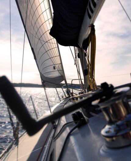 View from a sailboat on the water, showing sails and rigging against a clear sky.