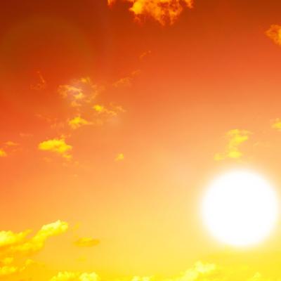 Bright sun in a clear orange sky with scattered yellow clouds, creating a warm and glowing atmosphere.