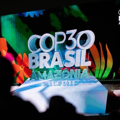 A large screen displays the COP30 Brasil Amazonia Belém 2025 logo with colorful foliage and silhouettes of people in the foreground.