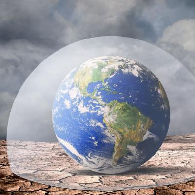 A glass dome encloses a globe showing the Americas, set on cracked, dry ground under a cloudy sky.