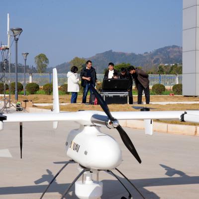 Four people stand by a black equipment case outdoors while a large white drone marked “XAMY” rests on the pavement in the foreground.
