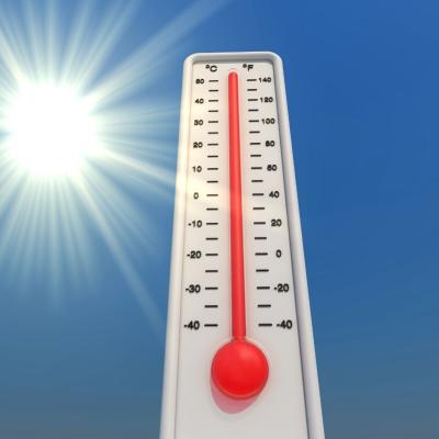 A thermometer showing a high temperature stands against a clear blue sky with the sun shining brightly in the background.