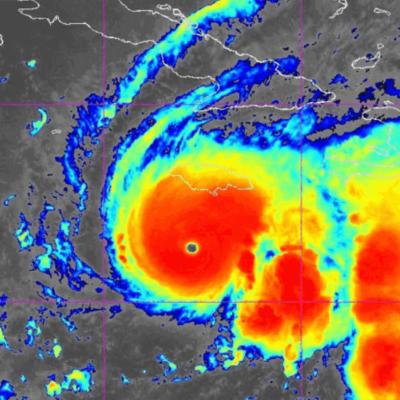 Satellite image shows a large hurricane with a clear eye, displaying intense red and yellow cloud bands indicating strong storm activity approaching land.