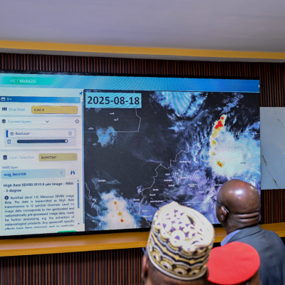 Several uniformed individuals look at a large digital screen displaying weather satellite data and maps dated 2025-08-18.