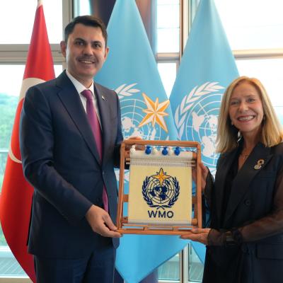 A man and woman stand together holding a WMO plaque, with Turkish and WMO flags visible in the background.