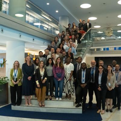 A large group of people posing for a photo on the stairs of a modern office building lobby.