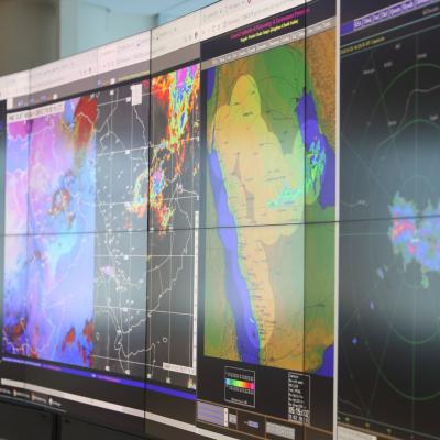 A wall of monitors displaying meteorological radar maps and weather data.